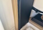 Tall black storage case stood upright in a small beige cabinet, next to a black mesh pocket.