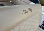 Close-up of light-colored boat seat upholstery with a brown Sea Ray logo and honeycomb stitching pattern in the background.