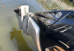 Close-up of a black Verado outboard motor mounted to a boat in calm water, showing the propeller and mounting brackets.