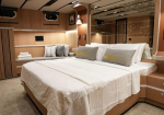 Luxurious bedroom in a wood-paneled cabin with a king bed, white linens, decorative throw pillows, and built-in storage.