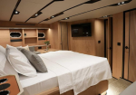 Luxurious bedroom cabin with a large white bed, gray pillows, and wooden paneling on a yacht or upscale hotel suite interior