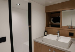 Modern bathroom vanity with rectangular white sink, wood cabinetry, and mirrored cabinet; glass shower enclosure on the left.
