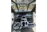 Boat cockpit helm with steering wheel, dual displays, and throttle controls in view from the captain's seat