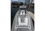 Luxury speedboat docked at a marina, viewed from the bow, showing gray-and-white quilted seating and a center console cockpit.