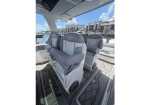 Two gray captain chairs with white quilted upholstery aboard a luxury motorboat, marina visible in the background on a sunny day.