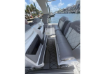 Luxurious boat cockpit with gray diamond-stitched seating along the sides, white console on the left, and a view of a marina with other boats in the background.