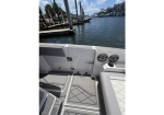 Rear cockpit of a white motorboat with gray patterned deck mats, docked in a marina.