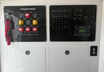 Marine electrical control panel with fuse switches on the left and a gauge/display panel on the right; red safety key hanging from the left panel; two white storage doors below.
