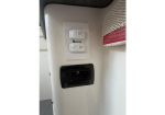 White wall with a dual light switch panel above a black rectangular control unit; a vent with a red label is on the right.
