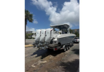 Powerboat on a dual-axle trailer with four outboard motors, parked in a lot on a sunny day.