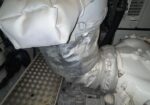 Insulated silver duct wrapped around a large white industrial machine, mounted on a diamond-plate floor.