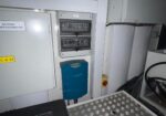 Industrial electrical cabinet: DC start power distribution panel with two breaker boxes and a blue mounted controller nearby in a machine room.