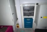 Electrical control panel with two meter boxes above a blue protective door; 'Danger High Voltage' label visible.