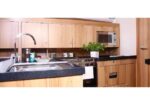 Kitchen with wood cabinets, stainless sink with curved faucet, and microwave above the stove on a black speckled counter.