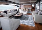 Luxurious yacht lounge with white sofas, wooden floors, and a coffee table, sea visible through large windows (panoramic ocean view).