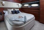 Luxurious bedroom aboard a yacht with a large bed, gray bedding, and dark wood paneling along the walls.