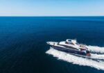 White luxury motorboat speeding across calm blue ocean, leaving a white wake behind it.