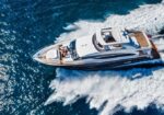 White motor yacht cruising at speed in deep blue water, leaving a foamy wake behind it.