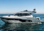 Luxury motor yacht sailing on calm blue sea with a gray hull and white superstructure.
