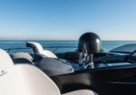 Luxurious boat cockpit with white seats, chrome controls, and a radar dome against a calm sea and blue sky horizon