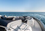 Luxurious yacht deck with gray cushions, pillows, and two wine glasses overlooking calm ocean.