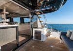 Open-plan lounge and galley on a luxury yacht, with wooden deck, stairs, and ocean view