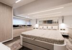 Luxurious modern bedroom with a large upholstered bed, neutral tones, and built-in wardrobes along both walls in a sleek cabin.