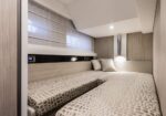 Cozy cabin bedroom with two twin beds pushed together, neutral patterned duvets, and soft bedside lighting.