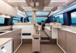 Luxurious yacht interior with a galley kitchen on the left, beige seating area on the right, and ocean visible through large windows