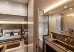Luxurious hotel suite: bed visible through glass partition and a marble bathroom vanity nearby.