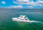 White luxury motor yacht cruising on emerald water with a distant coastline and blue sky above