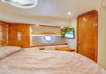 Luxurious boat cabin with a large bed, wood-paneled walls, and a mounted TV showing a tropical scene on the right wall