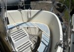 Interior of a small sailboat cockpit with coiled rope, cushioned benches, and metal rails nearby on a sunny day