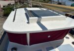 Top deck of a white sailboat with a beige furled mainsail overhead, dockside marina in the background.