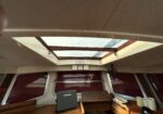 Interior view of a vehicle cabin with a rectangular skylight, exposed wooden beams, and a small desk area containing a Raymarine device.