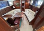Cozy boat cabin with cream upholstered seating around a wooden table and a central metal pole, wood-paneled walls.**(informative)