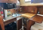 Boat galley with sink, stove, and microwave in a wood-paneled kitchenette.