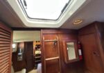Interior of a boat cabin with wood paneling, a skylight hatch in the ceiling, and a red fire extinguisher mounted on the wall.