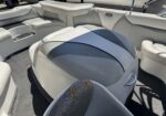 Interior of a pontoon boat with white/gray cushioned seating and cup holders visible in the armrest area with slight wear on the fabric.