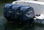 Three Yamaha V8 350 outboard motors mounted on the stern of a white boat in calm water.