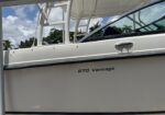 White motorboat hull with '270 Vantage' branding and chrome door handle, under a cloudy blue sky.