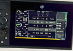 Upside-down view of a cockpit avionics touchscreen showing flight data such as speed, altitude, and engine/readout panels with control buttons on the sides.