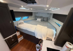 Cozy boat cabin with a large bed, gray bedding and pillows, and built‑in dark cabinets along the sides. - Informative image conveying a bedroom area on a yacht.