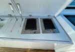 Outdoor boat galley with two stainless vent panels and cabinet doors above a white counter.
