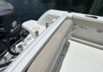 White boat cockpit with cushioned beige seat, Mercury outboard engine cover, and docked water in the background.