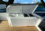 Open dual-compartment outdoor cooler on a boat with a wooden deck and water in the background, ready for drinks.