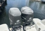 Two Mercury outboard motor covers mounted on the back of a boat at a marina.