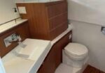 Wooden vanity with white countertop sink and a nearby toilet in a compact bathroom.