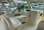 White leather seating area inside a luxury boat cockpit, with large panoramic windows and a helm console nearby