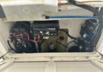 Open boat battery compartment showing a central battery with surrounding wiring, red/black cables, and connectors.